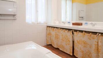 Ein Badezimmer mit einem weißen Waschbecken, einem Spiegel und einem Duschvorhang mit Blumenmuster.