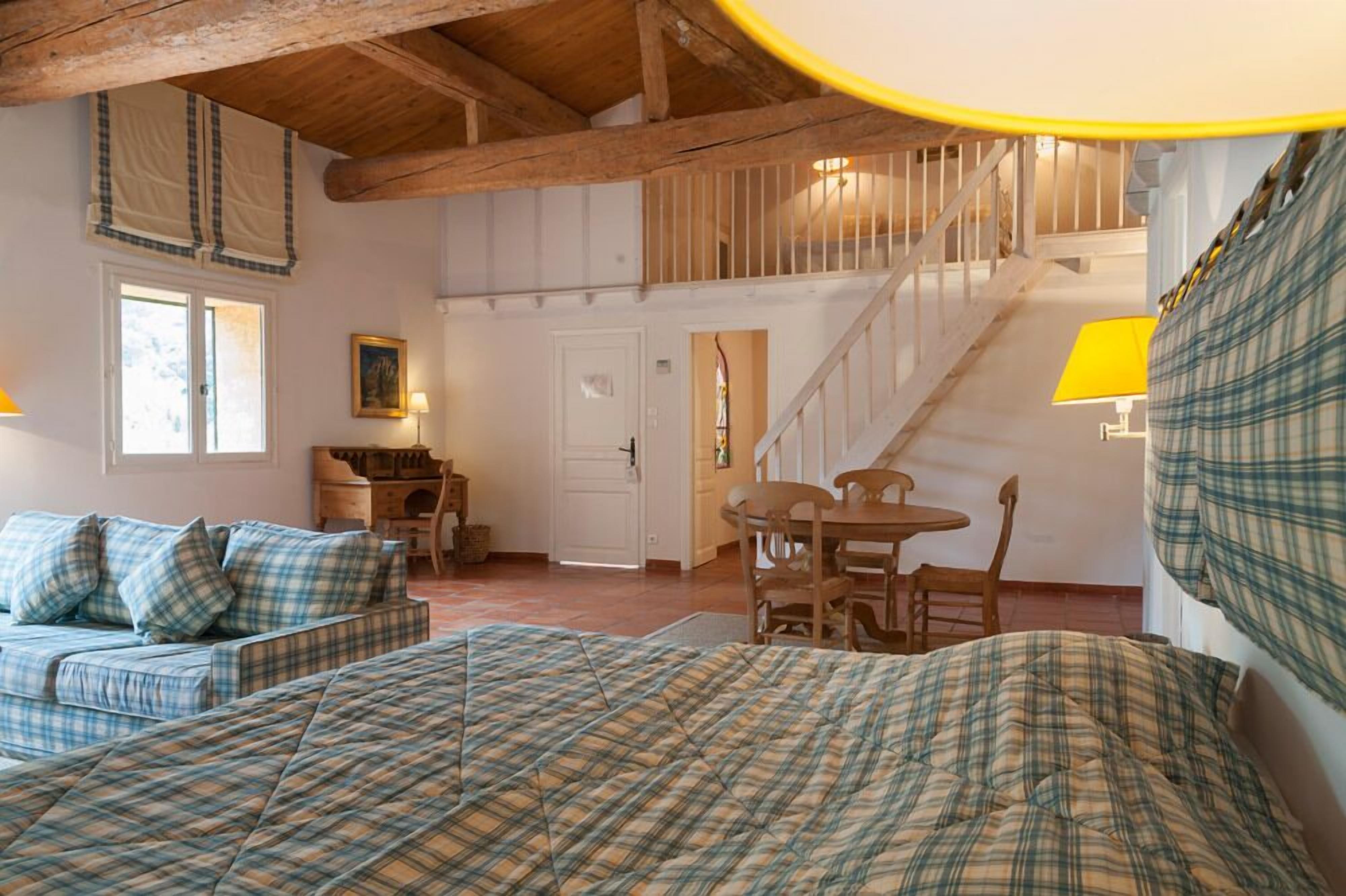 Ein gemütliches Zimmer mit einem Bett, einer Holzbank, einem Tisch und einer Treppe.