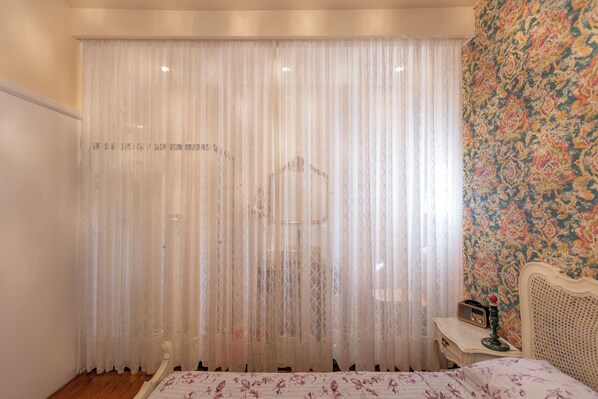 Une chambre à coucher avec un lit, une table de chevet, une radio et un rideau.