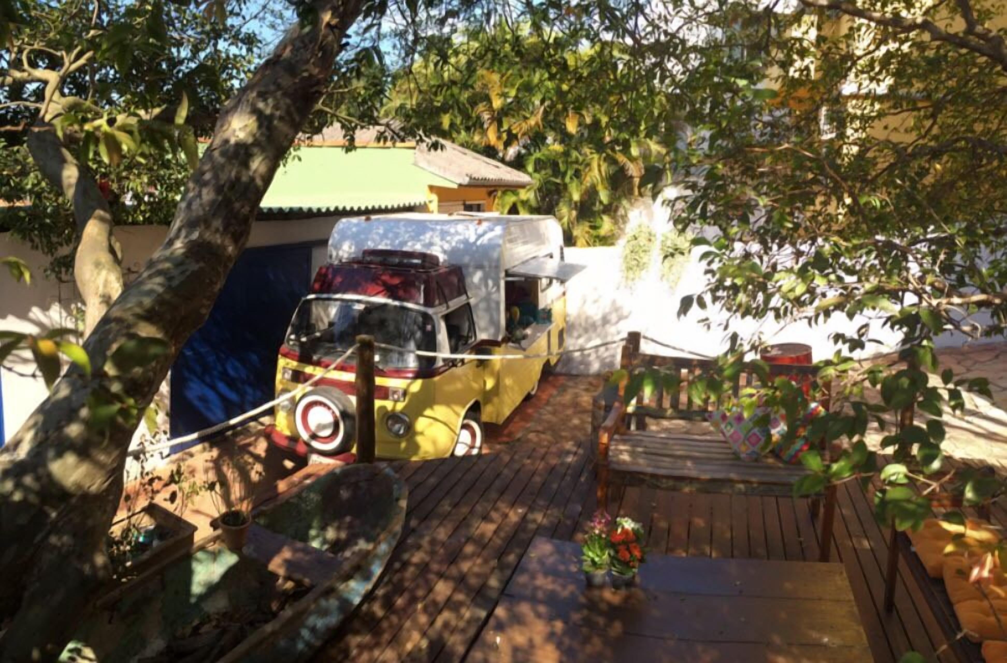 A wooden deck with a yellow car and a green-roofed building.