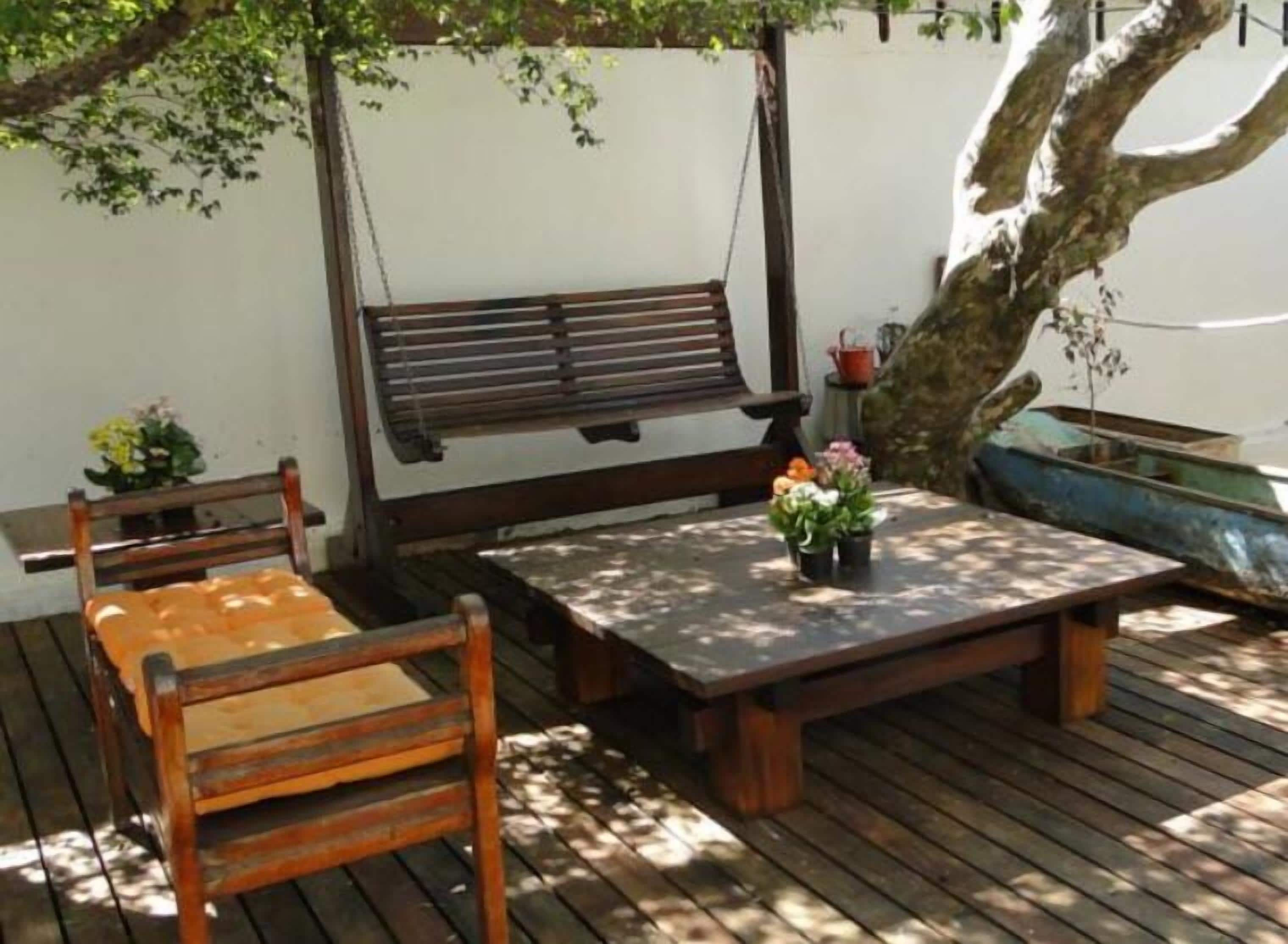 A wooden deck with a bench, a table, and potted plants.