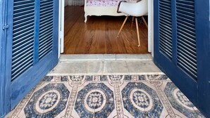 Un dormitorio con cama, mesita de noche, lámpara y ventana con cortinas.
