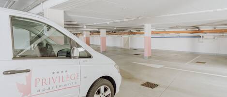 A white van with "PRIVILEGE apartments" branding parked in a clean, empty parking garage with white pillars and a tiled floor.