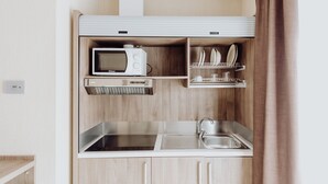 A compact kitchenette with a microwave, oven, and sink. - Privilege Apartments (Vimercate)