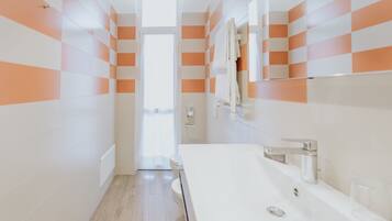 A modern bathroom with a white sink, mirror, and orange and white tiled walls.