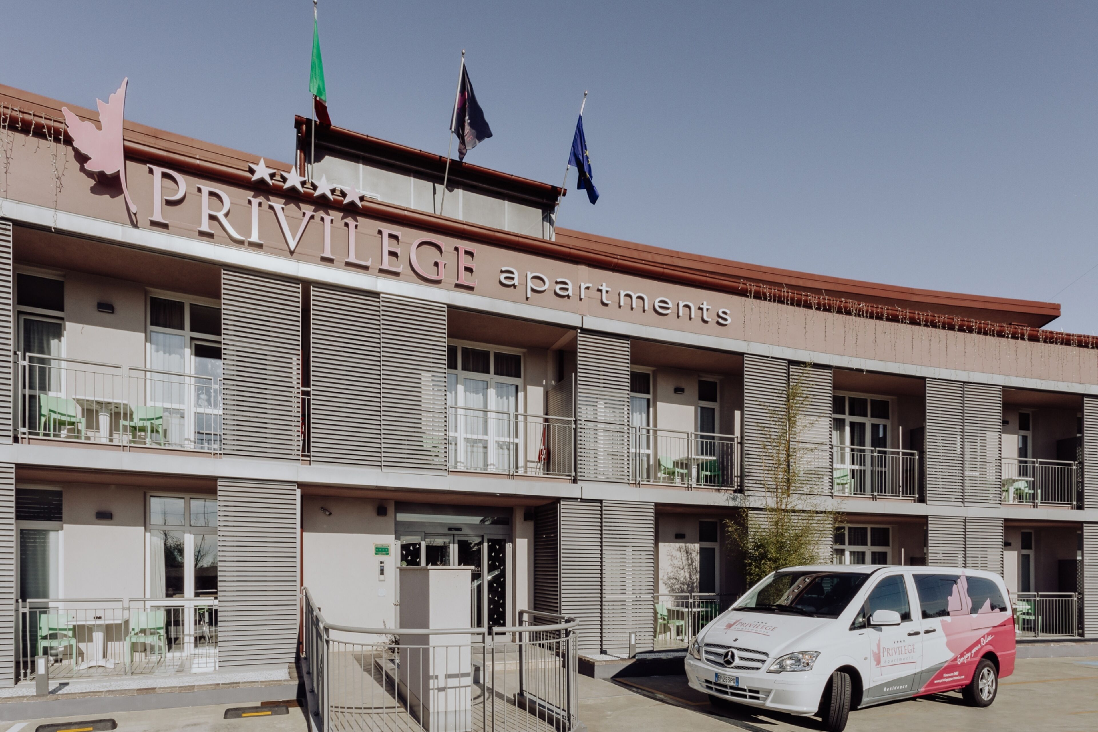 Un immeuble à plusieurs étages portant l’enseigne « Appartements PRIVILEGE » et doté de balcons avec des garde-corps.