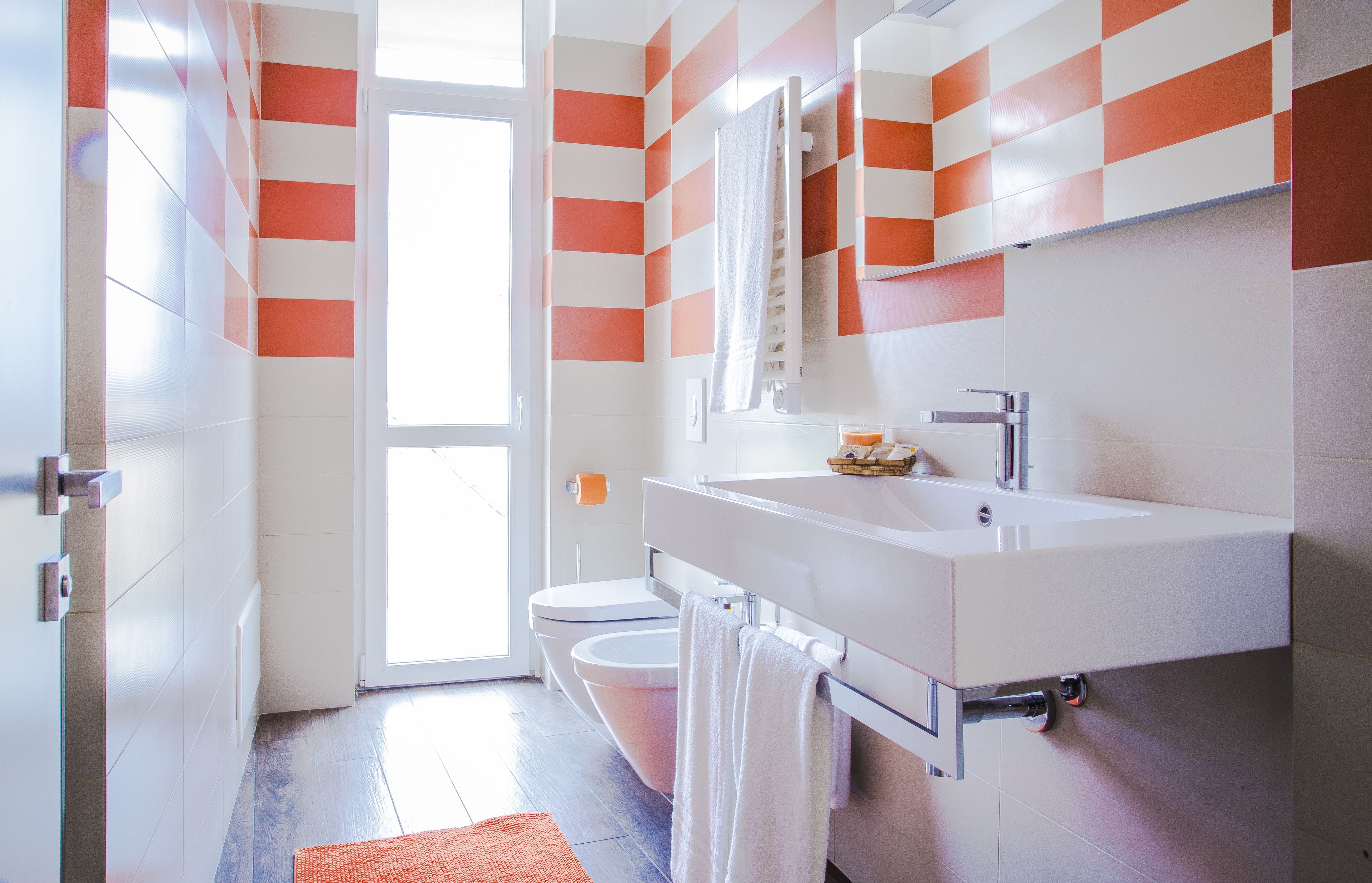 A modern bathroom with a white sink, mirror, and toilet.