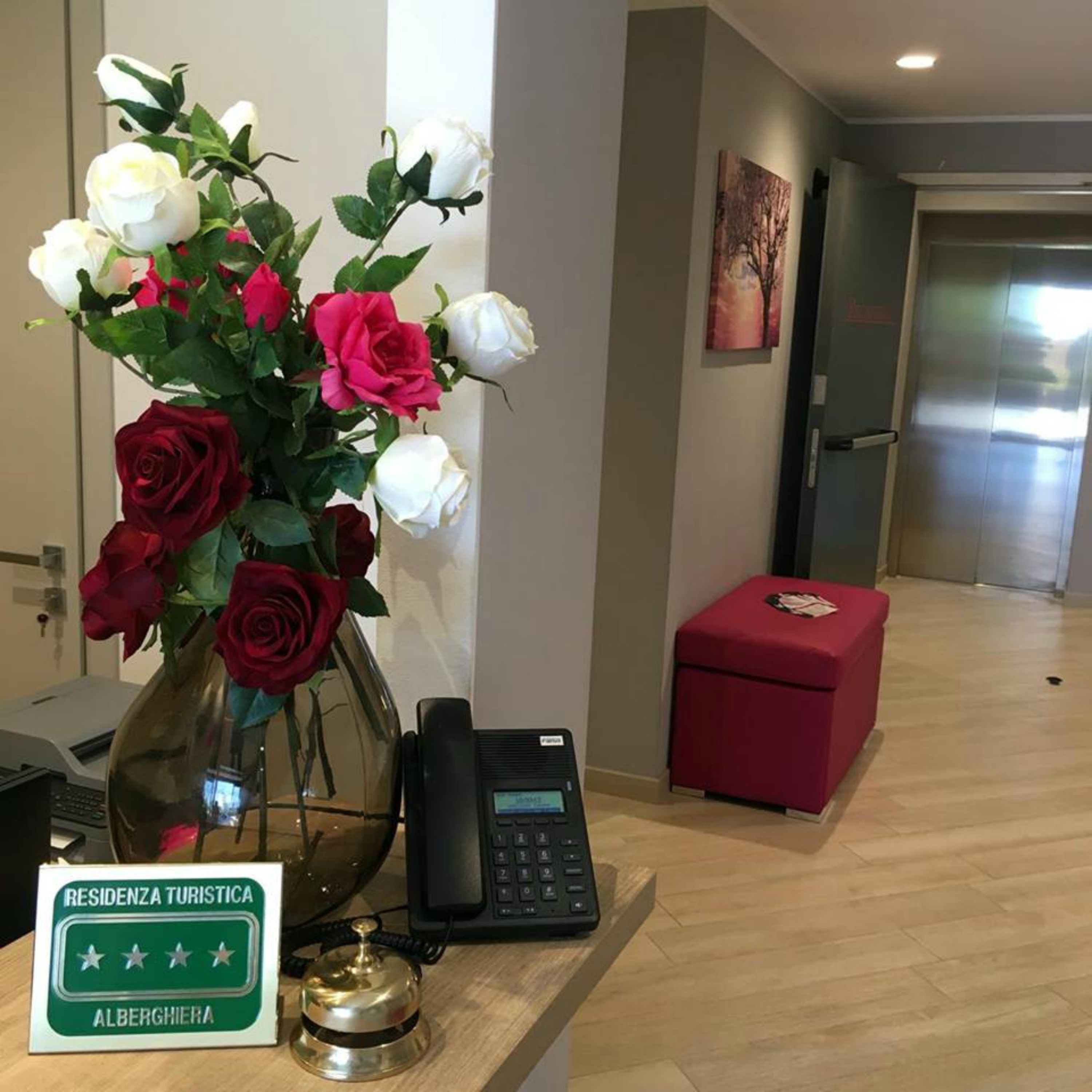 A reception desk with a vase of flowers, a phone, and a sign indicating a 4-star rating.