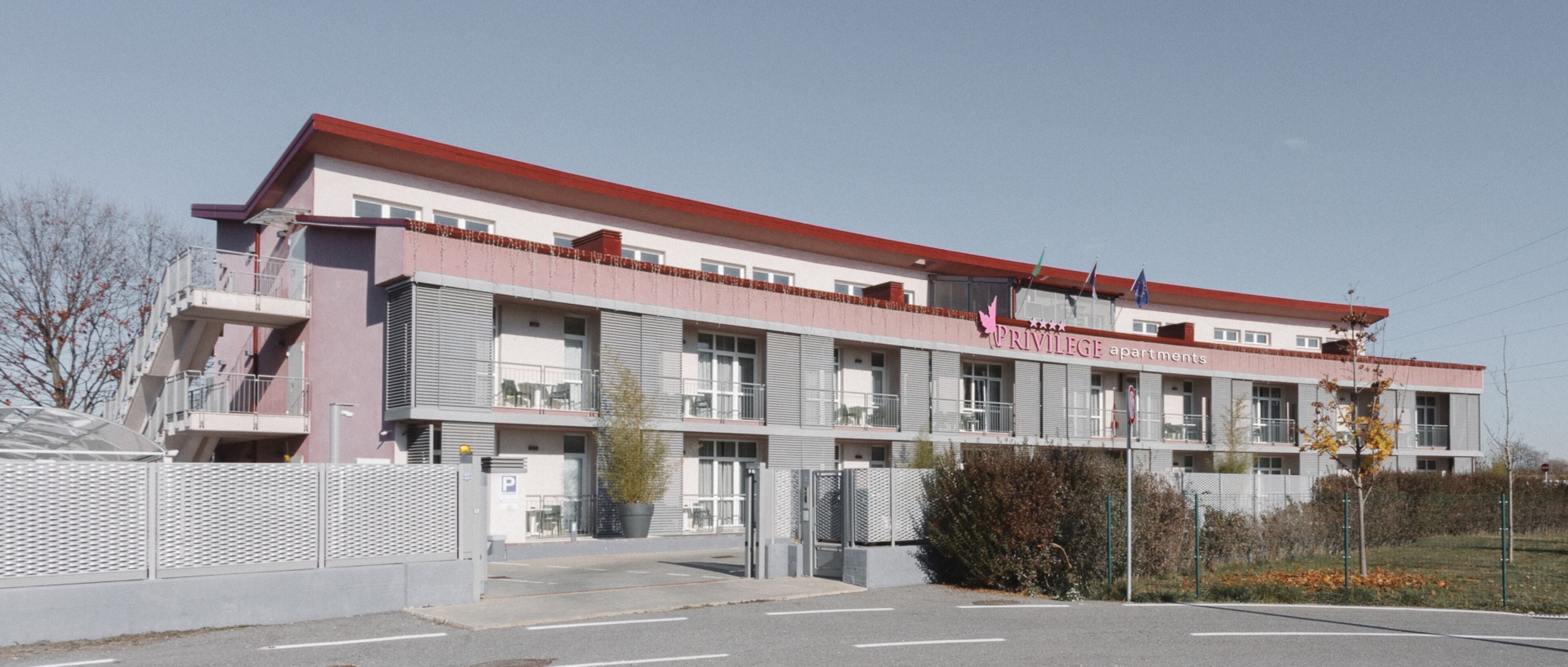 A multi-story building with a red roof and balconies. The building has a sign that reads "Privilege Apartments."