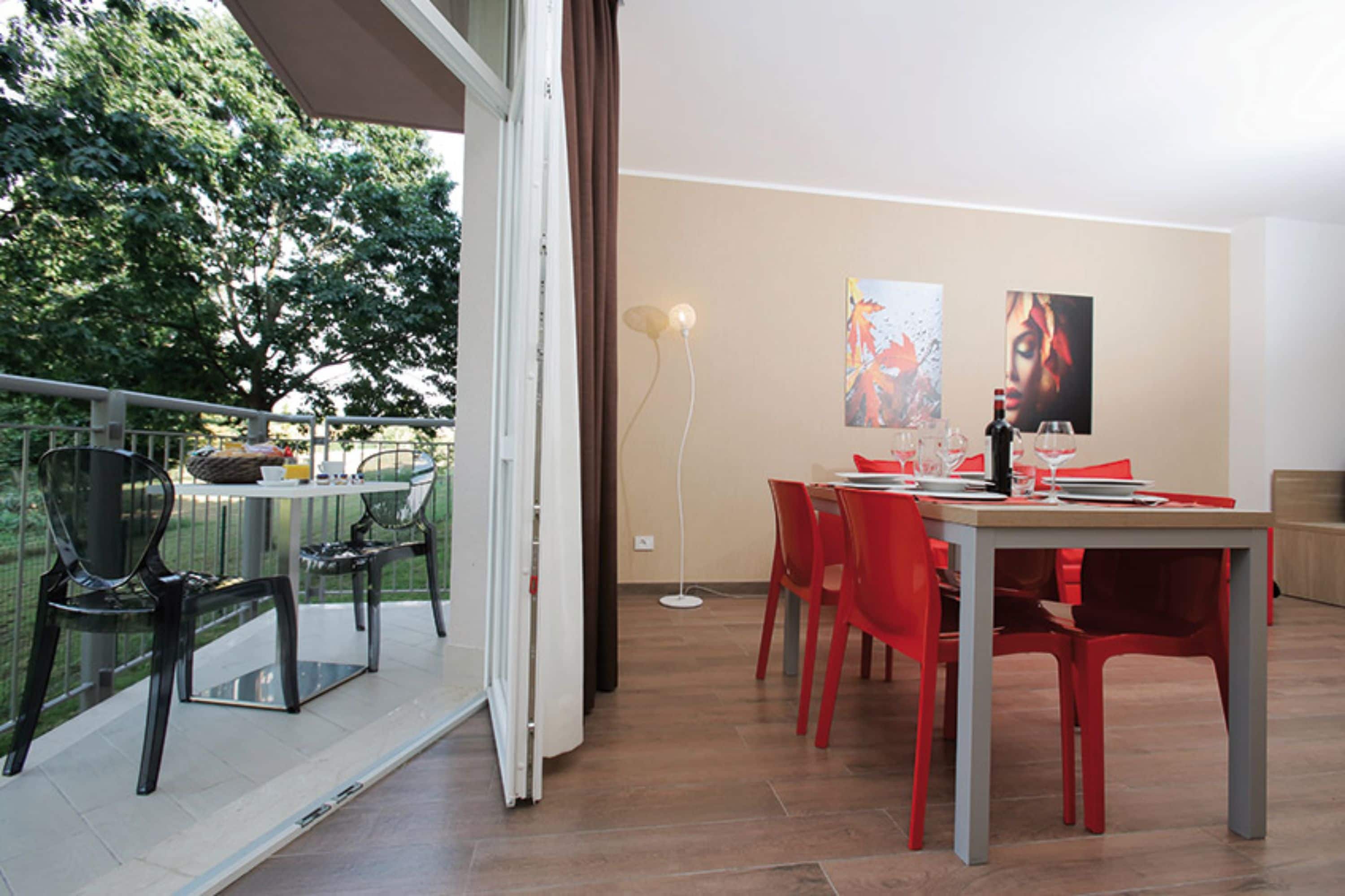 Un comedor con una mesa dispuesta para dos, sillas rojas y vistas al exterior.