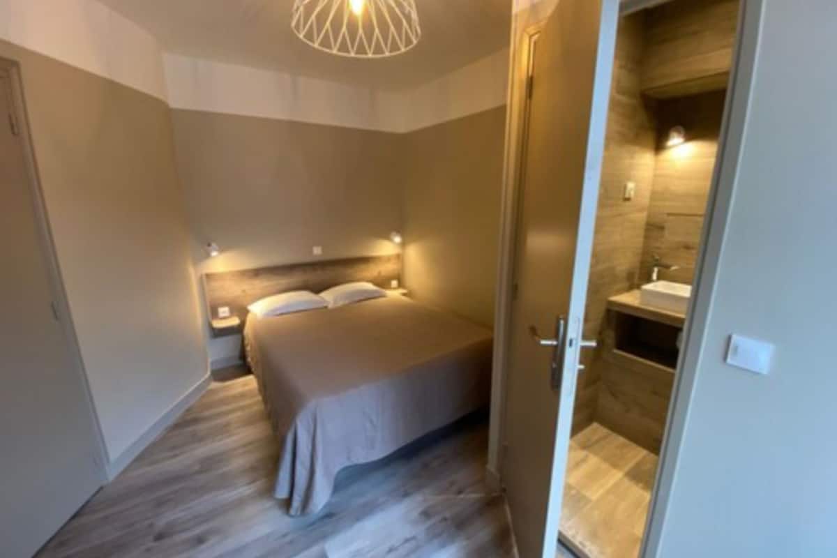 A bedroom with a bed, bedside tables, and a modern pendant light.