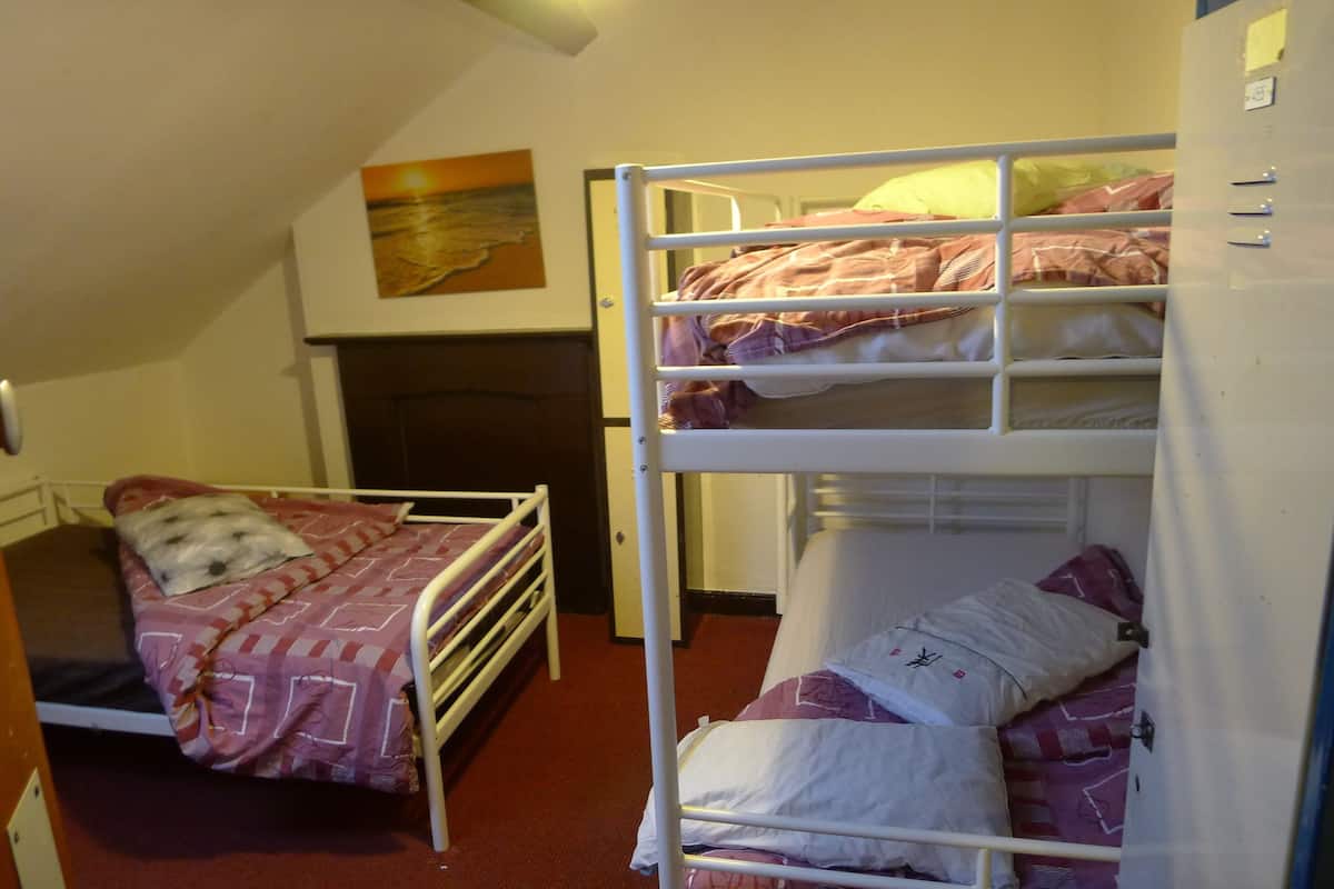 A bunk bed room with a bed on the left and a bunk bed on the right.