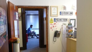 A hallway with a reception desk, a refrigerator, and a sign that reads "IS FEIDIR LINN". - Lagan Backpackers (Belfast)