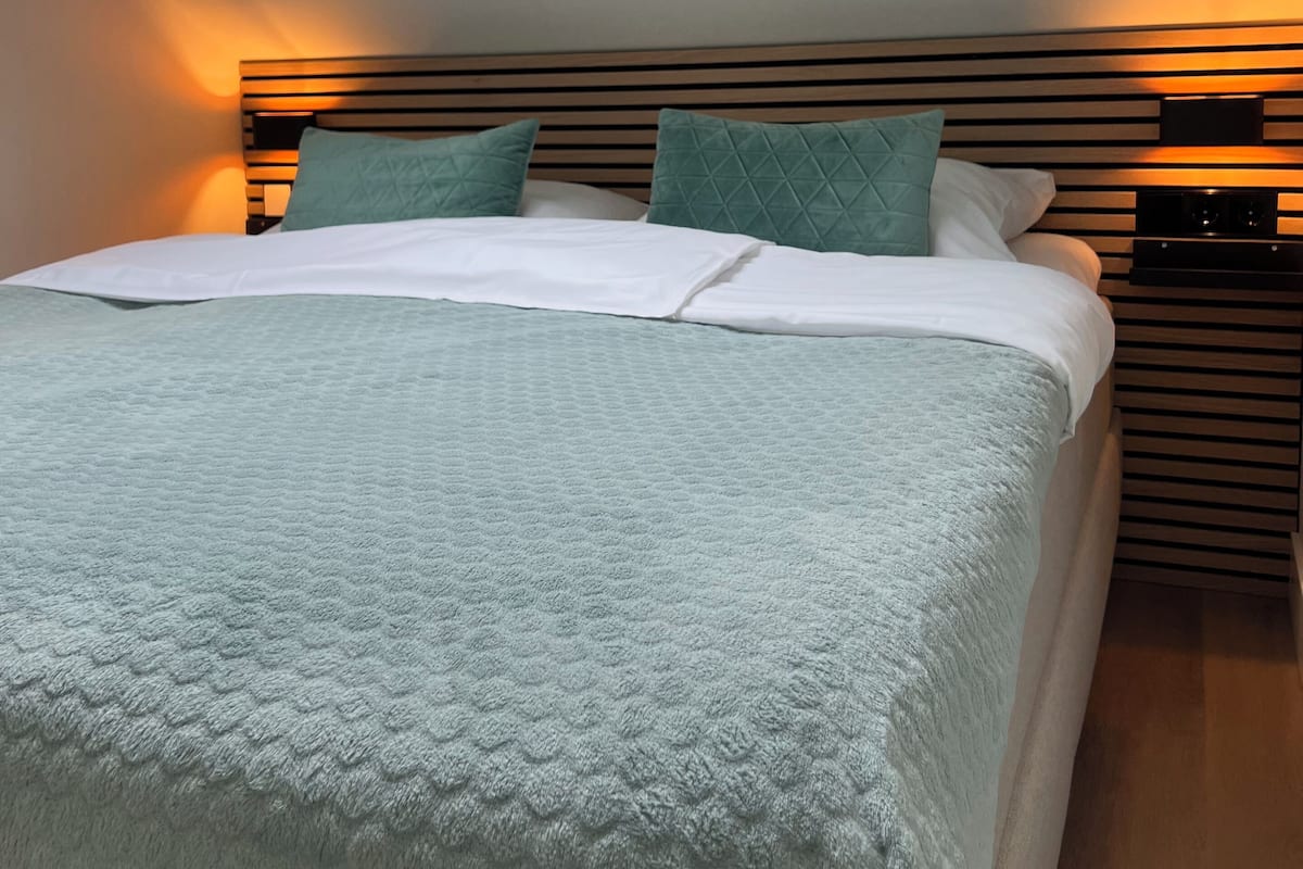 Een moderne slaapkamer met dakraam, een bed met een gewatteerde spreidek en een houten hoofdbord.