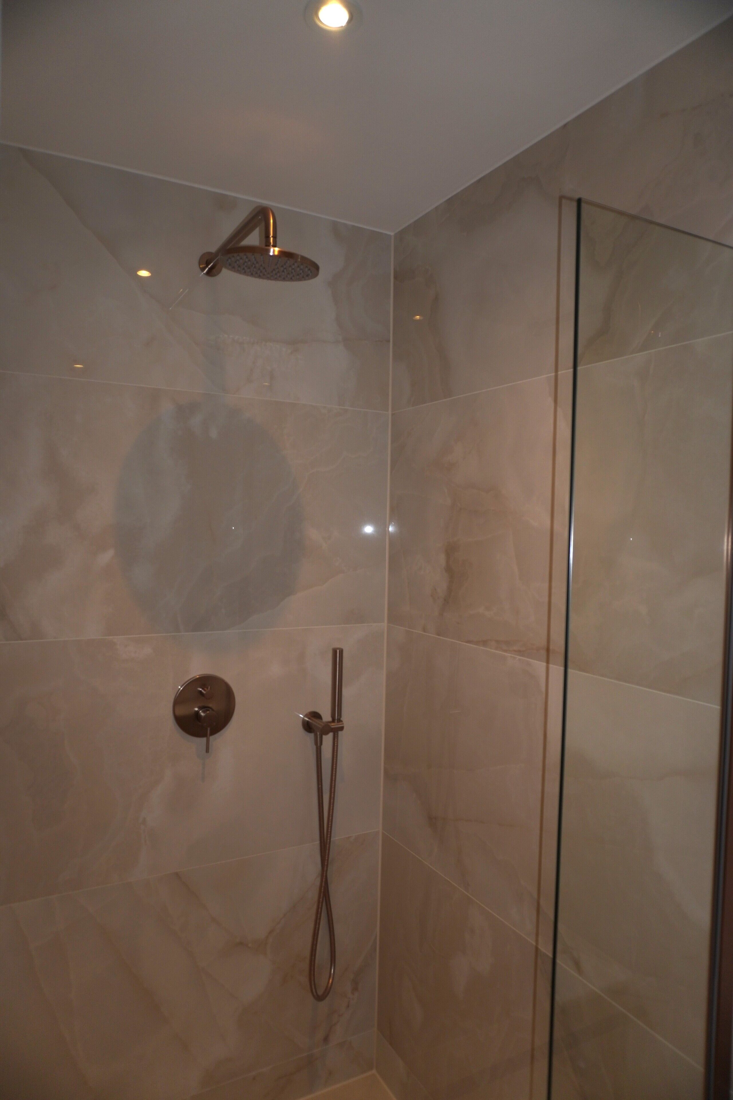 A modern shower with a handheld showerhead and a wall-mounted control.