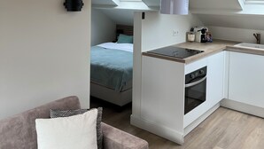 Een compact appartement in moderne stijl, met een kitchenette, een eethoek en een slaapkamer met dakramen.