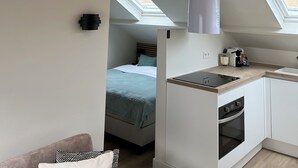Een moderne keuken met een inbouwoven, een klein kookeiland en een dakraam boven de eethoek.