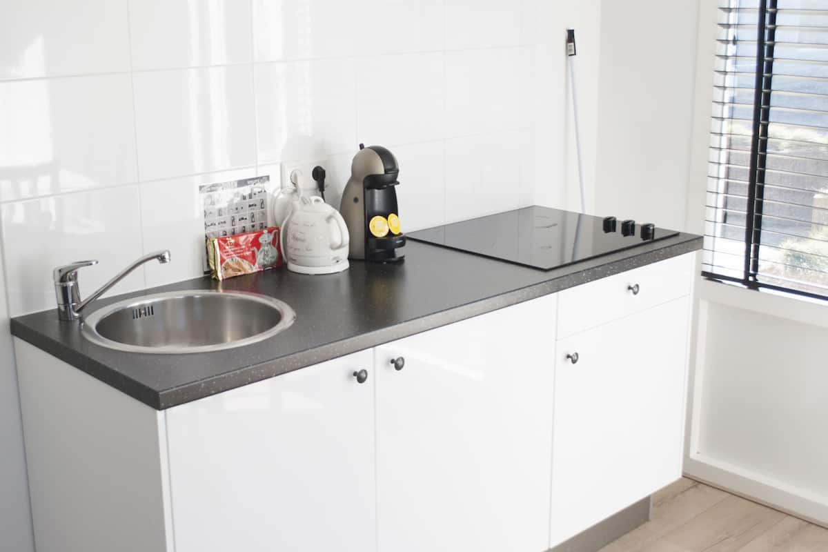 Een moderne keuken met een roestvrijstalen spoelbak, waterkoker en koffiezetapparaat op het aanrecht.