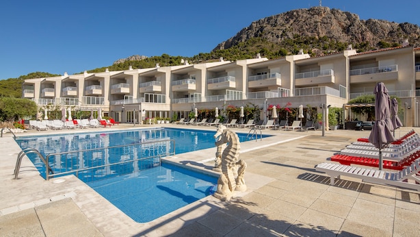 A hotel with a swimming pool, lounge chairs, and a mountain backdrop. - Centremar (Torroella de Montgrí)