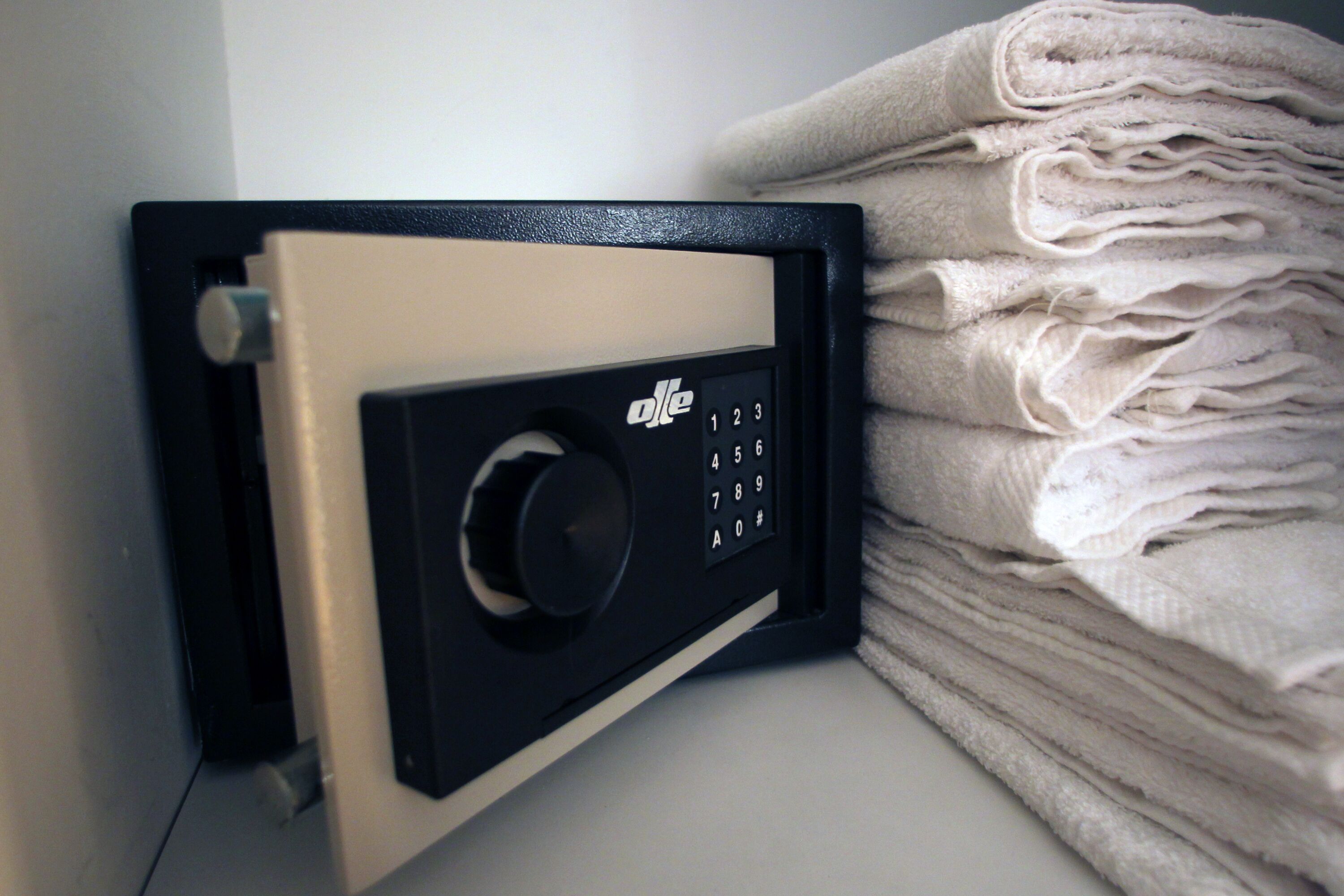 A black safe with a numeric keypad, placed next to a stack of folded towels.