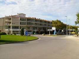 A multi-story building with a commercial ground floor, a roundabout, and a clear sky.