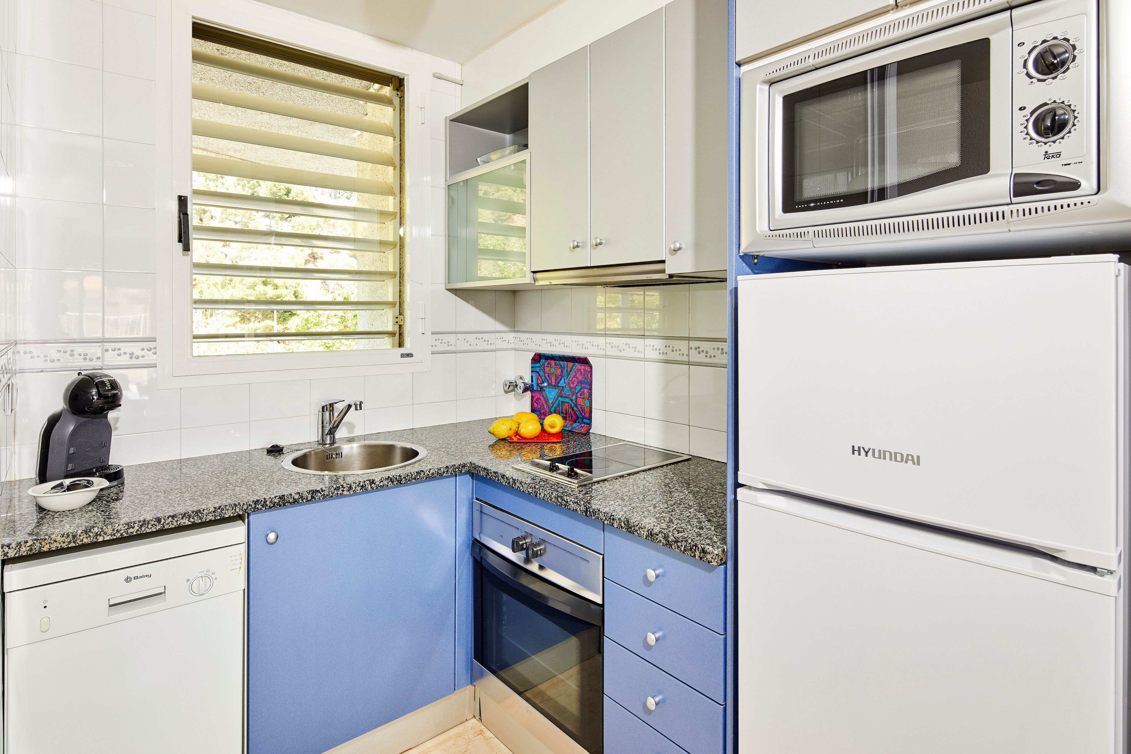 Een keuken met een ingebouwde magnetron, een spoelbak en een vaatwasser.
