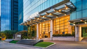 A modern hotel with a glass facade, a prominent entrance with a canopy, and a landscaped area with a small pool. - Le Meridien Saigon (Ho Chi Minh City)