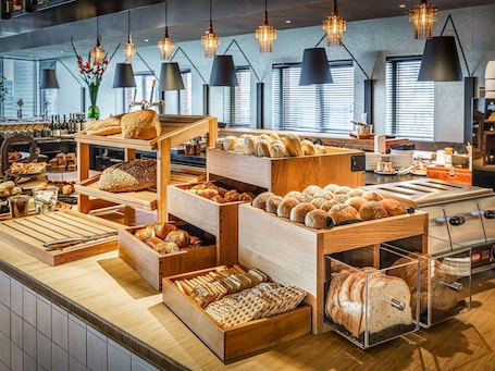 A bakery display with various breads and pastries.. Mercure Hotel Amsterdam Sloterdijk Station