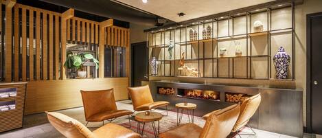 Un hall d’entrée moderne avec des fauteuils en cuir, un comptoir d’accueil en bois et un mur décoratif agrémenté d’étagères.
