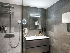 Ein modernes Badezimmer mit einer Duschkabine, einem Waschtisch mit Spiegel und einem Handtuch an der Wand.