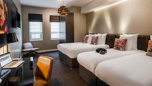Une chambre d’hôtel avec deux lits, un bureau avec un ordinateur portable, une chaise et une grande fenêtre.