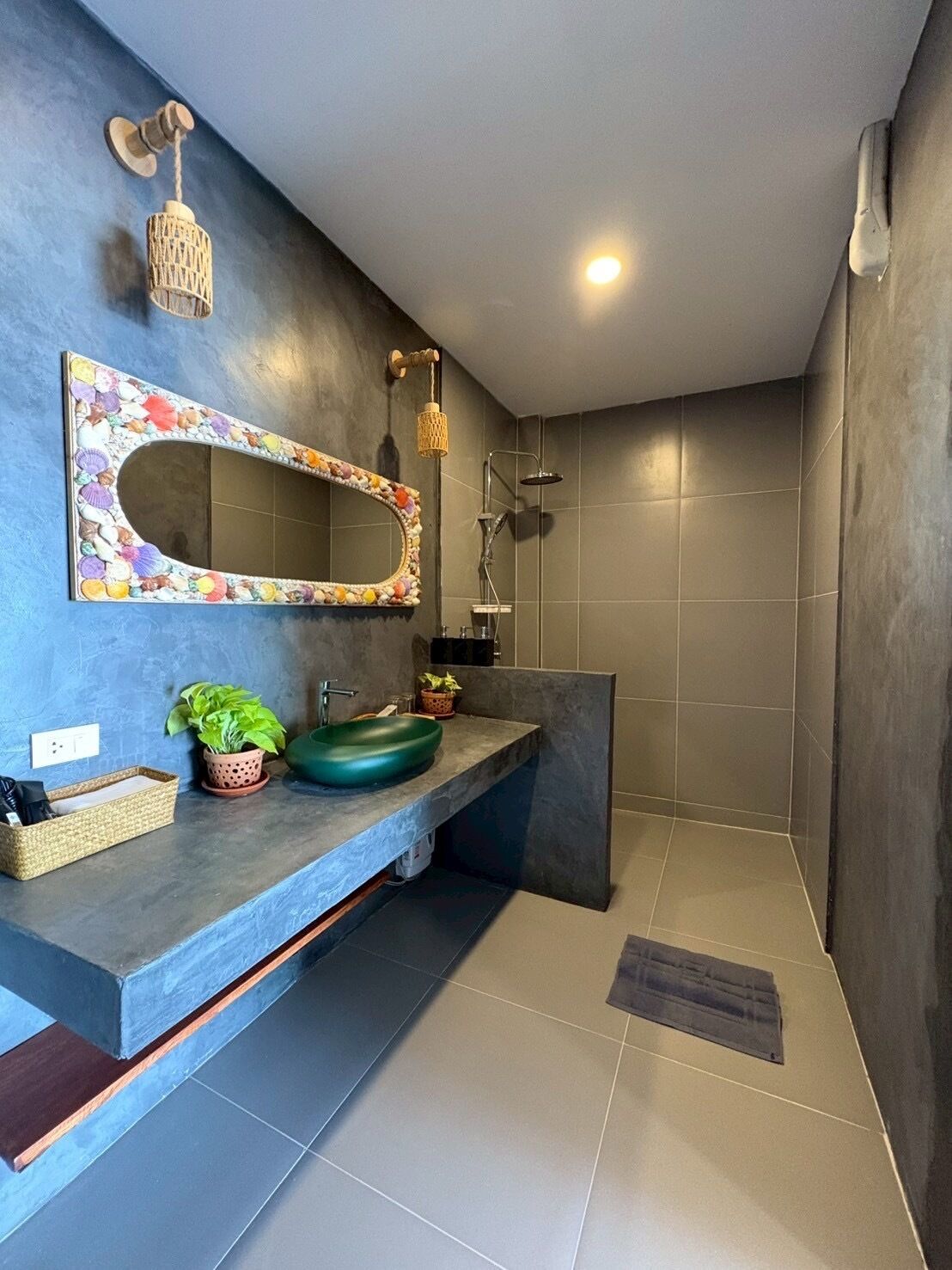 A modern bathroom with a large mirror, a green sink, and a shower.