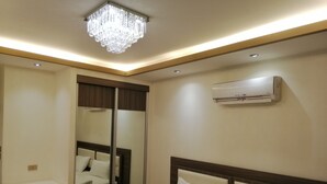 Una habitación de hotel con cama, espejo, lámpara en el techo y aire acondicionado.