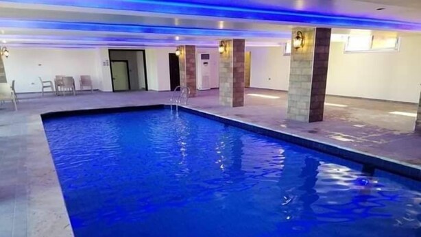 Una piscina interior con agua cristalina, un trampolín y suelo de baldosas.