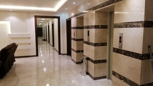 Un pasillo de hotel con una larga galería, paredes de mármol y un cesto de basura.