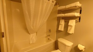 Un baño con bañera, inodoro y un perchero con toallas.