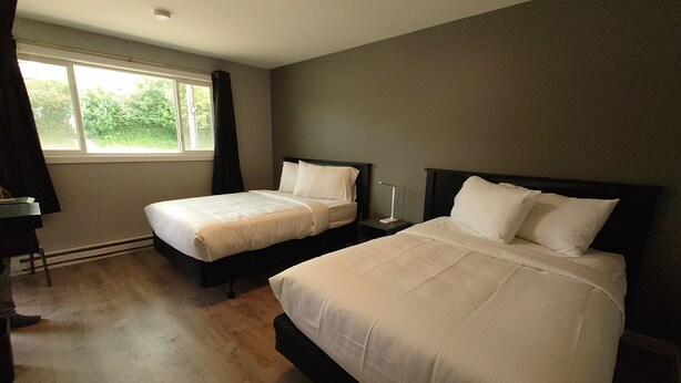 Habitación de hotel con dos camas, un escritorio y una ventana con cortinas.