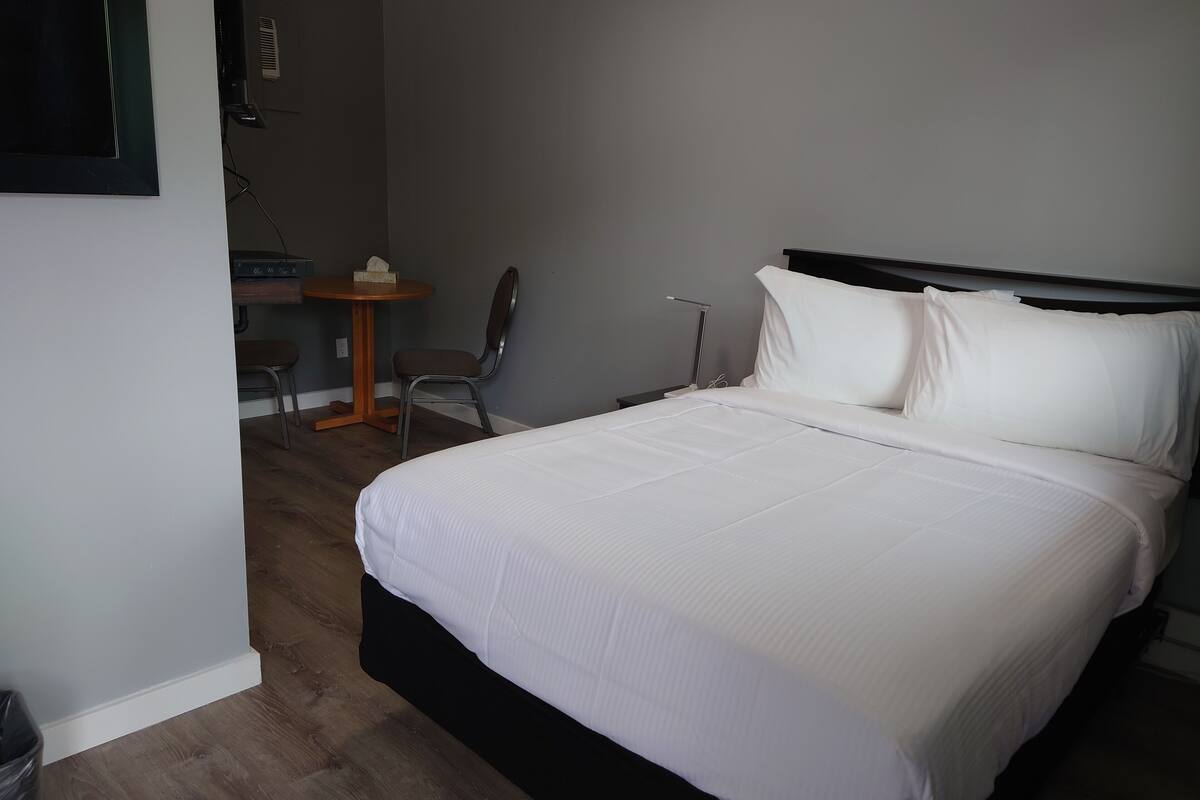 A neatly made bed with white linens in a hotel room.