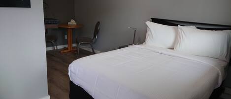 A neatly made bed with white linens in a hotel room.