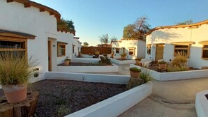 A courtyard with white buildings, wooden beams, and potted plants.