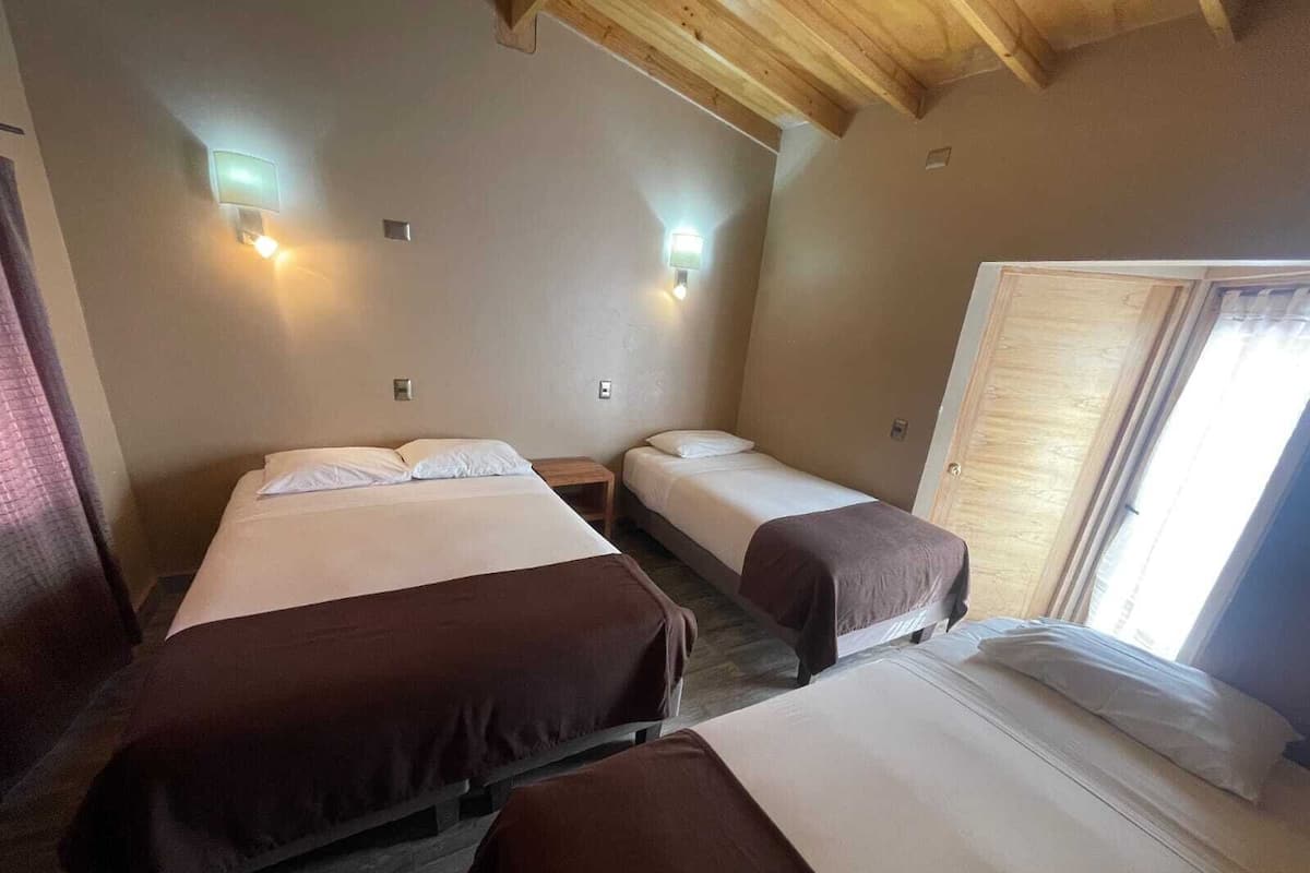 Een kamer met twee bedden, elk met een houten hoofdbord, en een raam met uitzicht op het exterieur.
