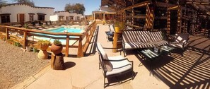 A poolside area with lounge chairs, a pool, and a wooden pergola.