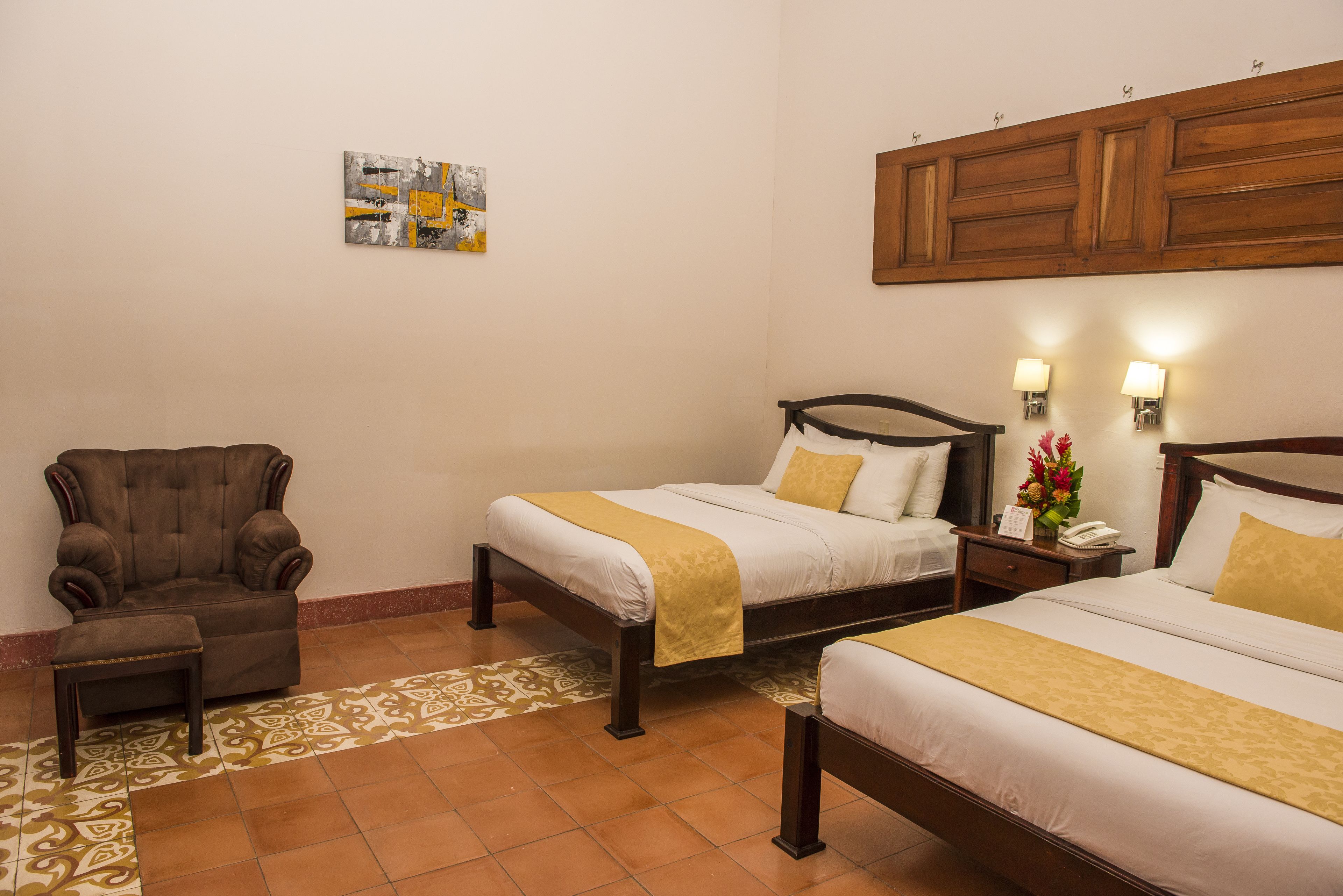 A hotel room with two beds, a sofa, a small table, and a decorative wall piece.
