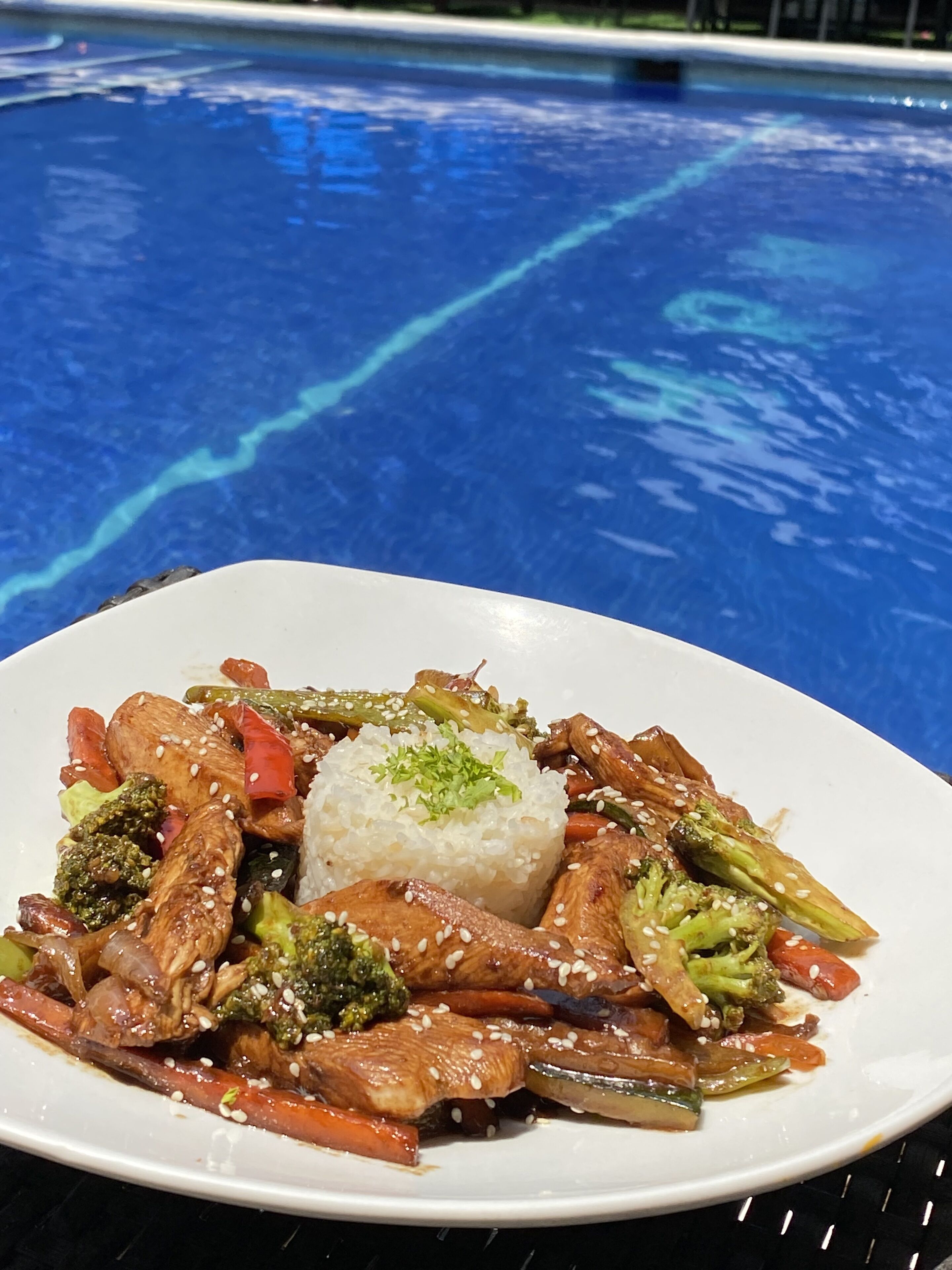Un plato de verduras y carne salteadas, acompañado de arroz, servido en un plato blanco.