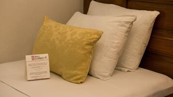 A bed with two pillows and a sign on the side.