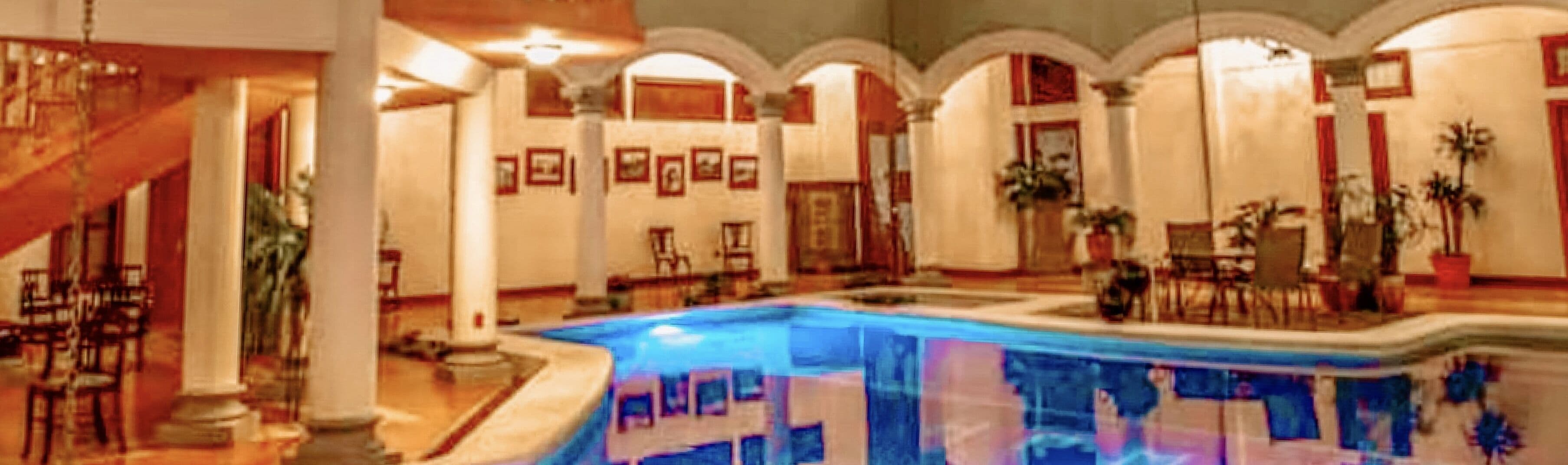 Un vestíbulo amplio con piscina central, varias zonas de descanso y una escalera que conduce a los pisos superiores.