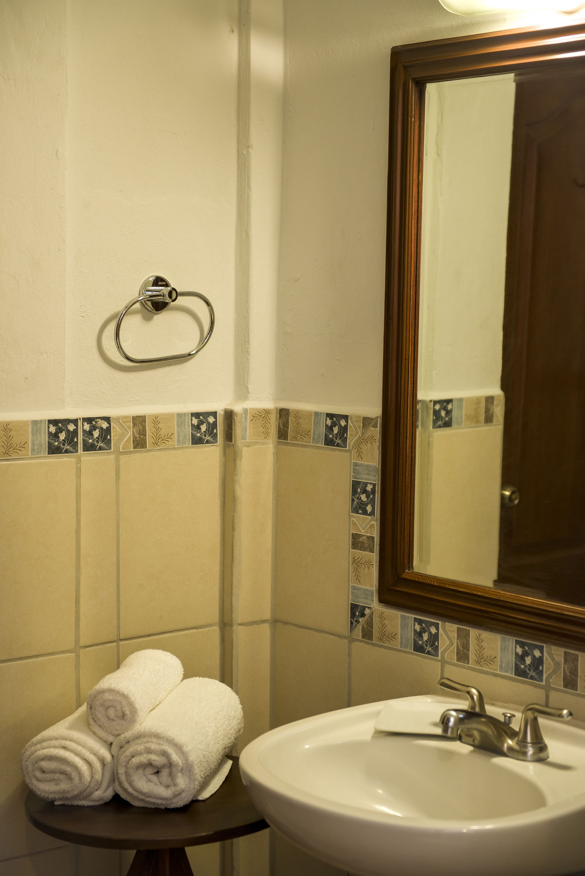 A bathroom with a sink, mirror, and towel rack.