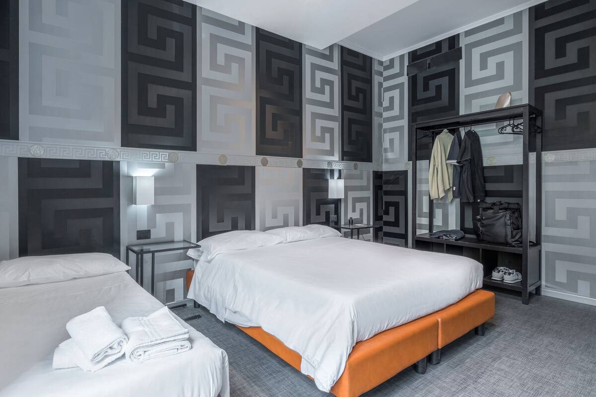 A hotel room with two beds, a wardrobe, and a mirror.