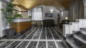 A lobby with a marble floor, a reception desk, a sofa, a statue, and a staircase. - Hotel Argentina (Florence)