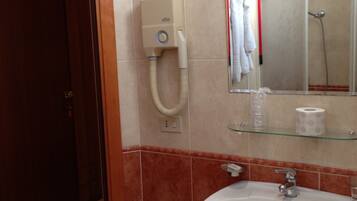 A bathroom with a sink, mirror, towel rack, and a shower.